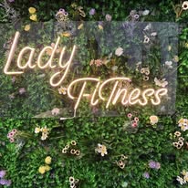 Lady Fitness neon sign on a flower wall at the studio