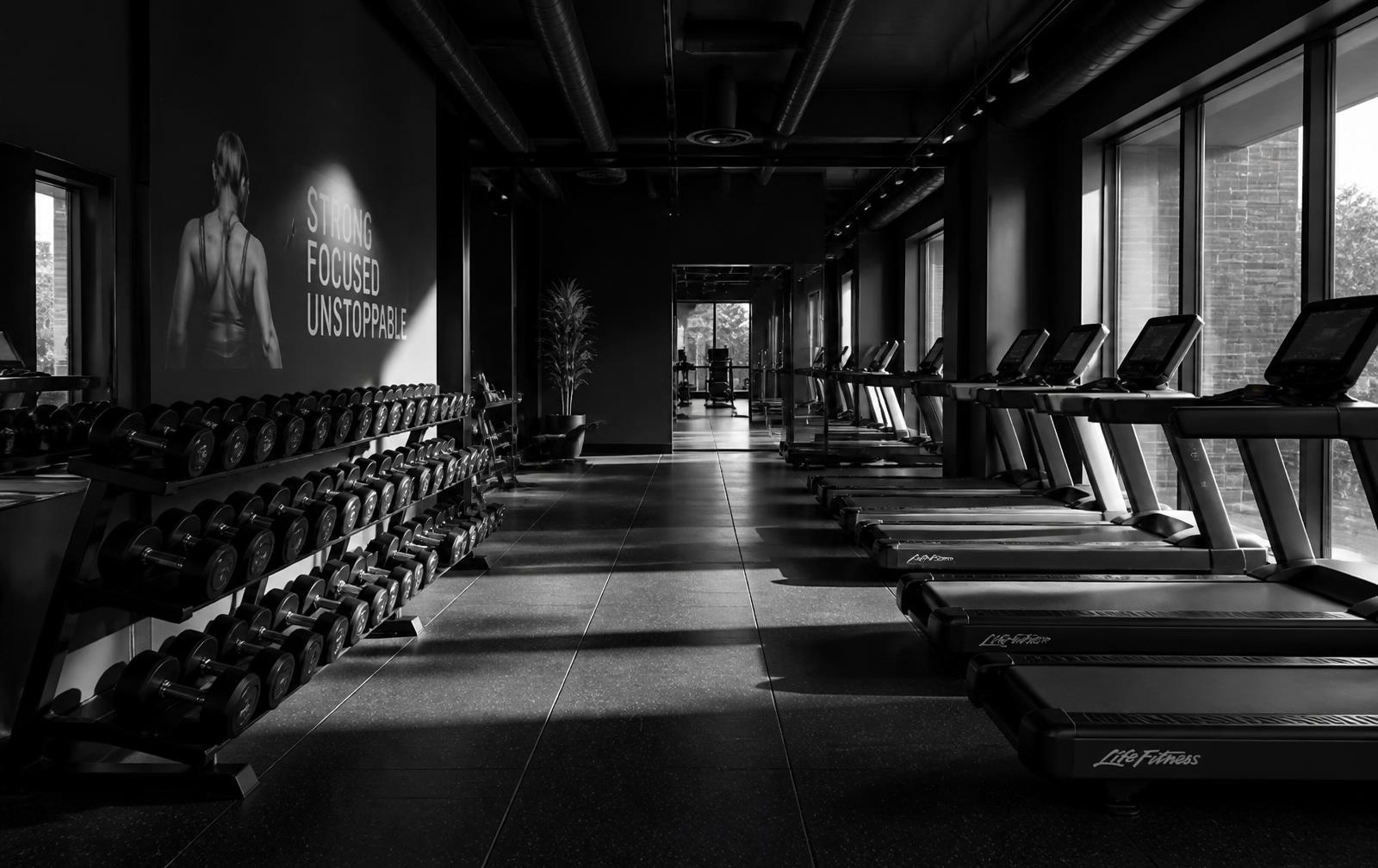Black and white view of the Lady Fitness training floor with dumbbells and treadmills